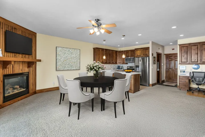 Dining room with ceiling fan, light colored carpet, a large fireplace, an office area, and recessed lighting