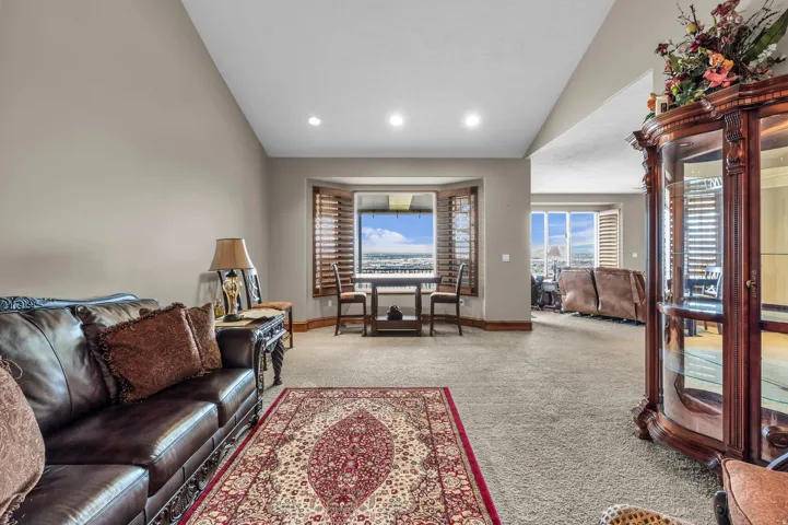 Carpeted living area with lofted ceiling and recessed lighting