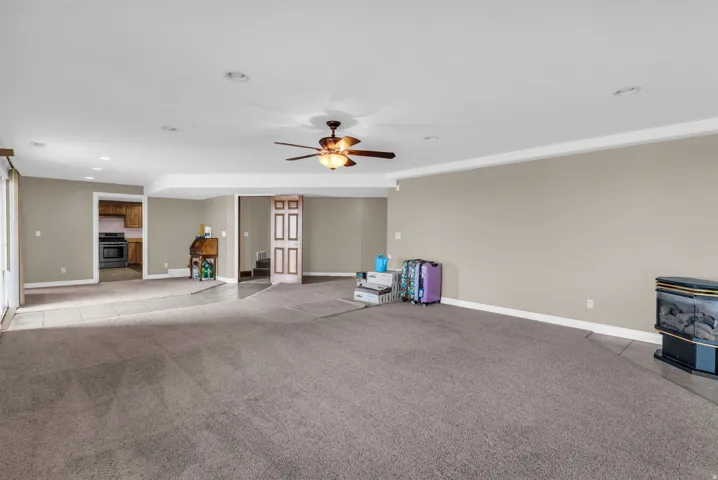 Unfurnished living room with ceiling fan, a wood stove, light carpet, and recessed lighting
