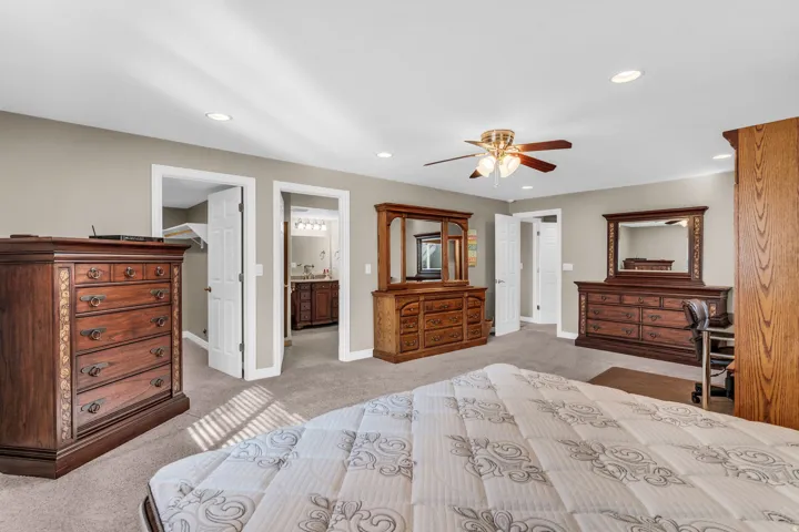 Bedroom featuring a spacious closet, light colored carpet, recessed lighting, connected bathroom, and a ceiling fan