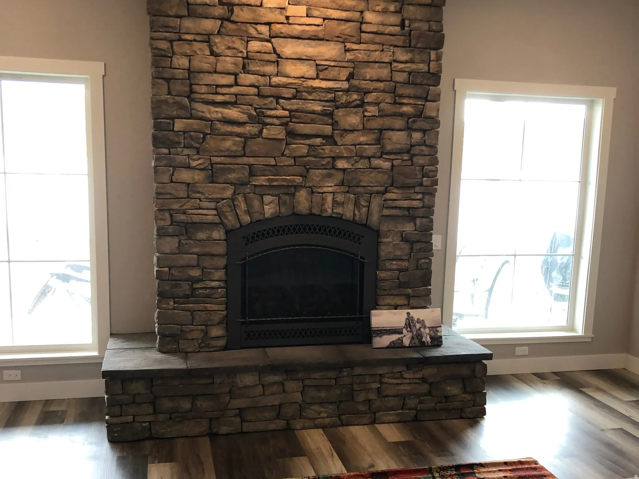 Living area featuring a stone fireplace, wood finished floors, and a ceiling fan