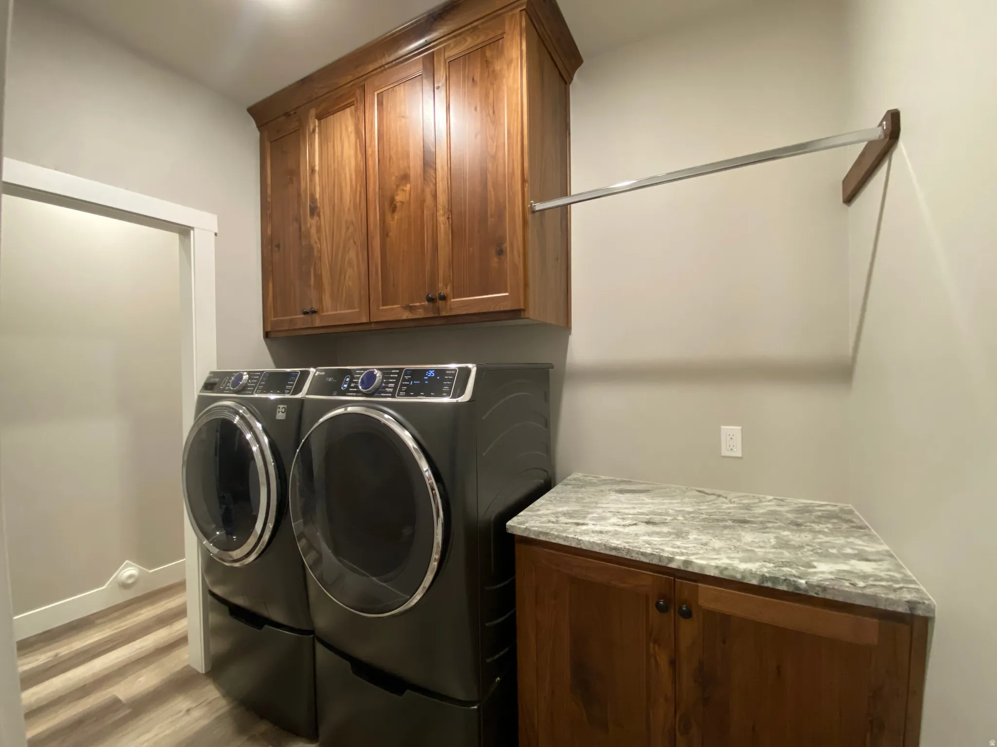 Laundry room with cabinet space, washing machine and dryer, and wood finished floors