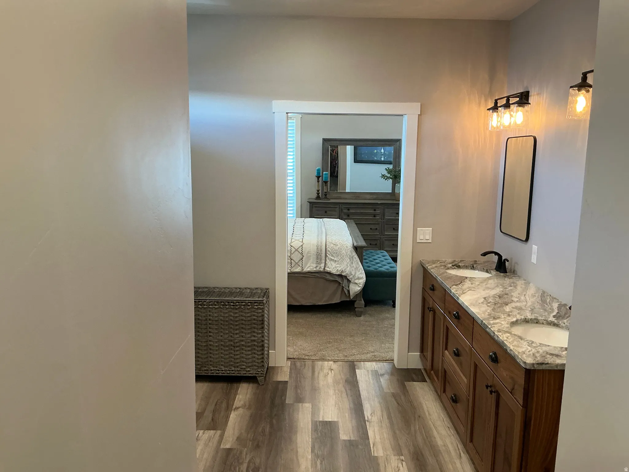 Bathroom with dark wood finished floors, double vanity, and connected bathroom