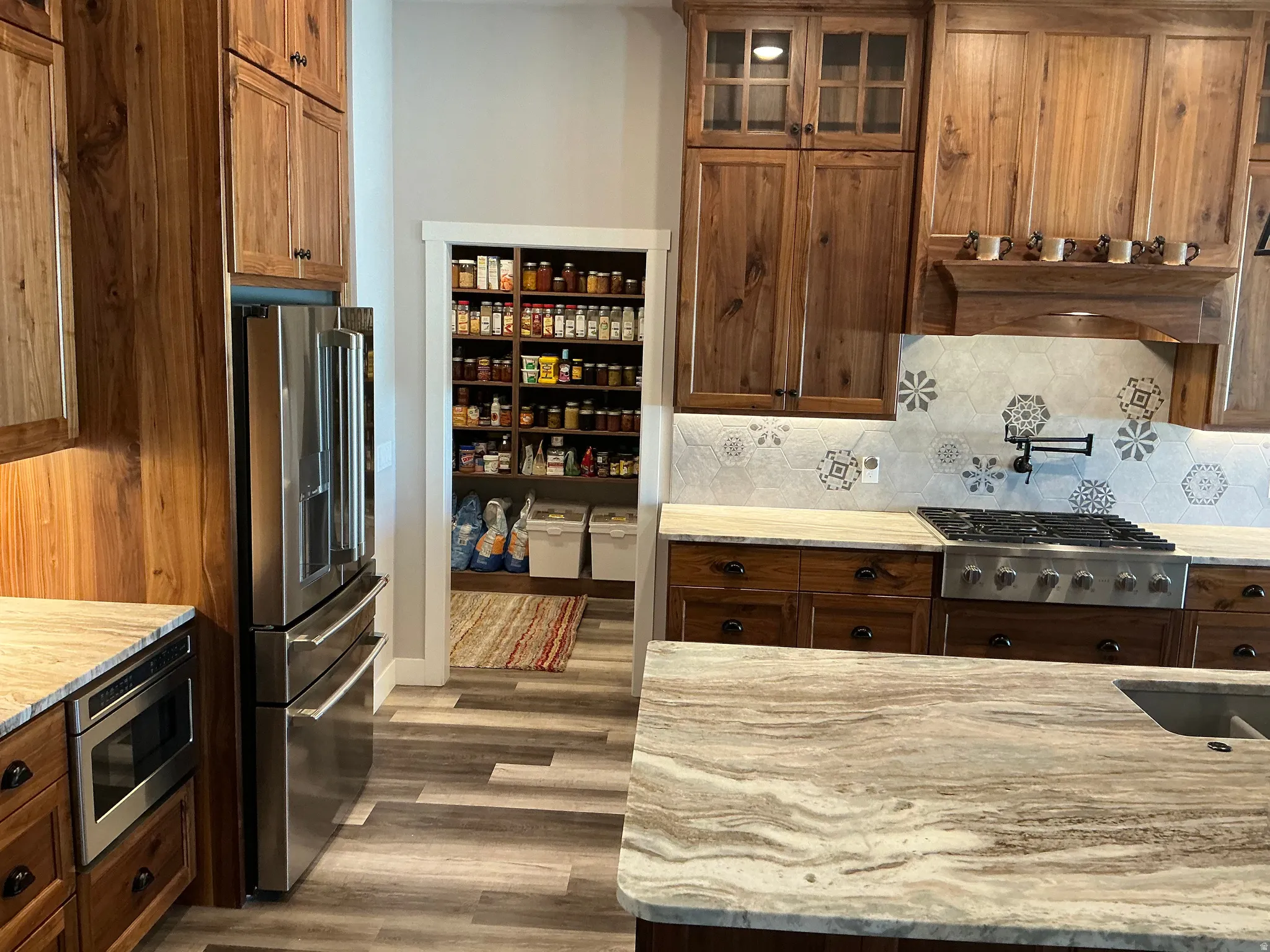 Kitchen featuring stainless steel appliances, light stone counters, backsplash, and wood finished floors