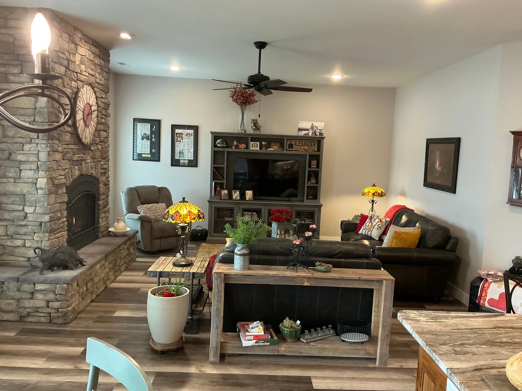 Living area with a stone fireplace, wood finished floors, ceiling fan, and recessed lighting