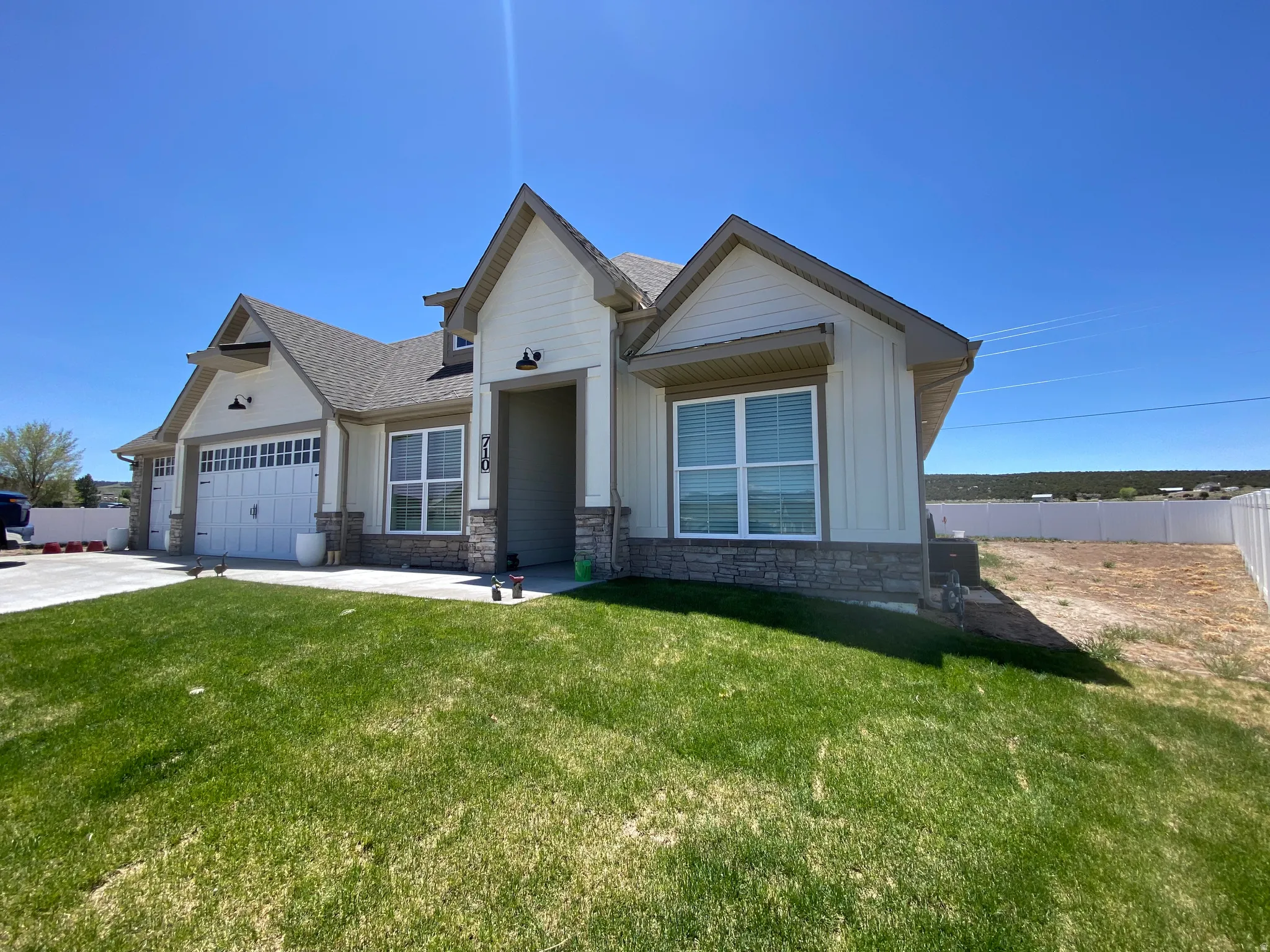 View of front of house featuring stone siding, a shingled roof, an attached garage, and concrete driveway