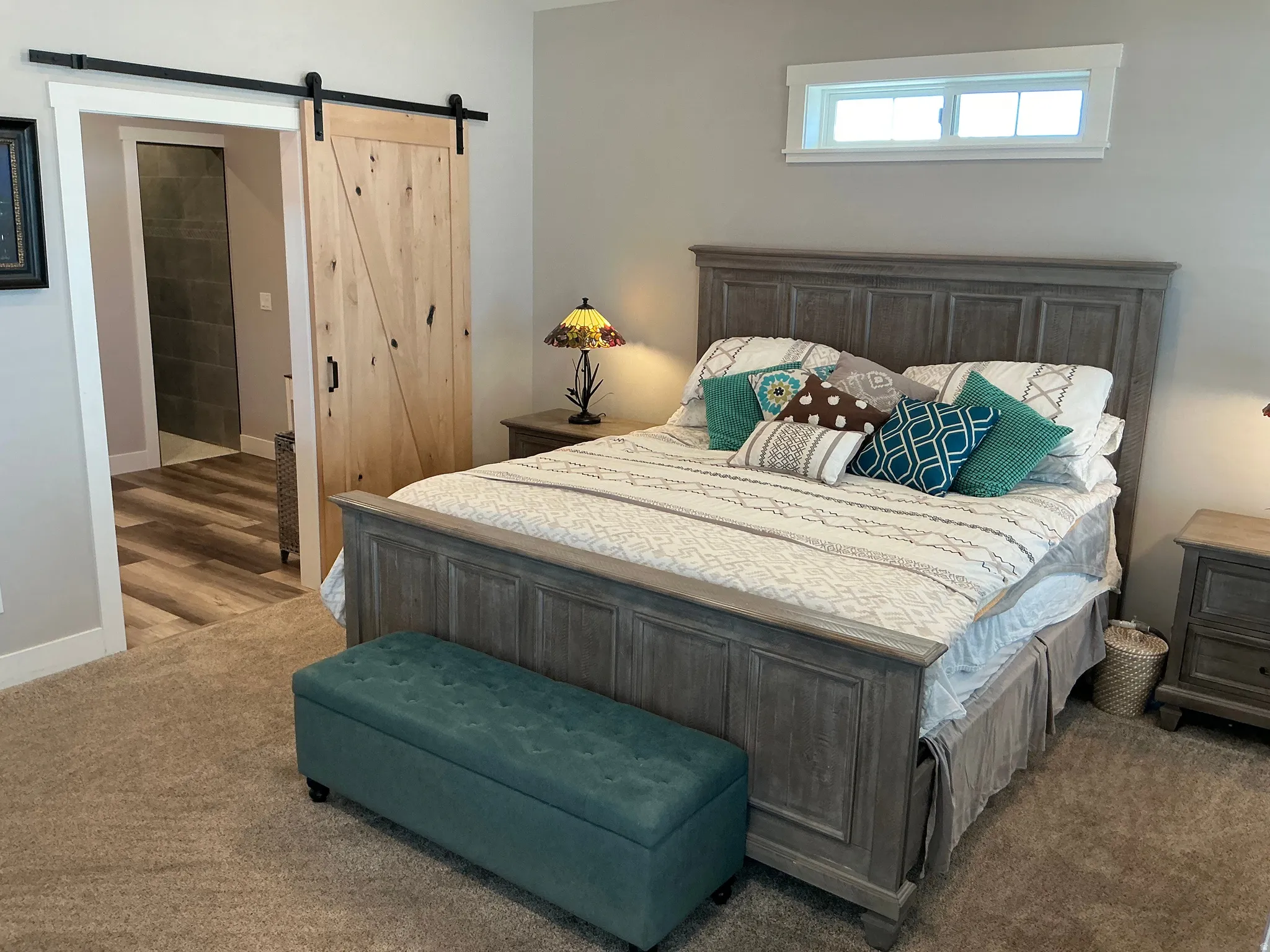 Bedroom featuring a barn door, carpet flooring, and ensuite bathroom