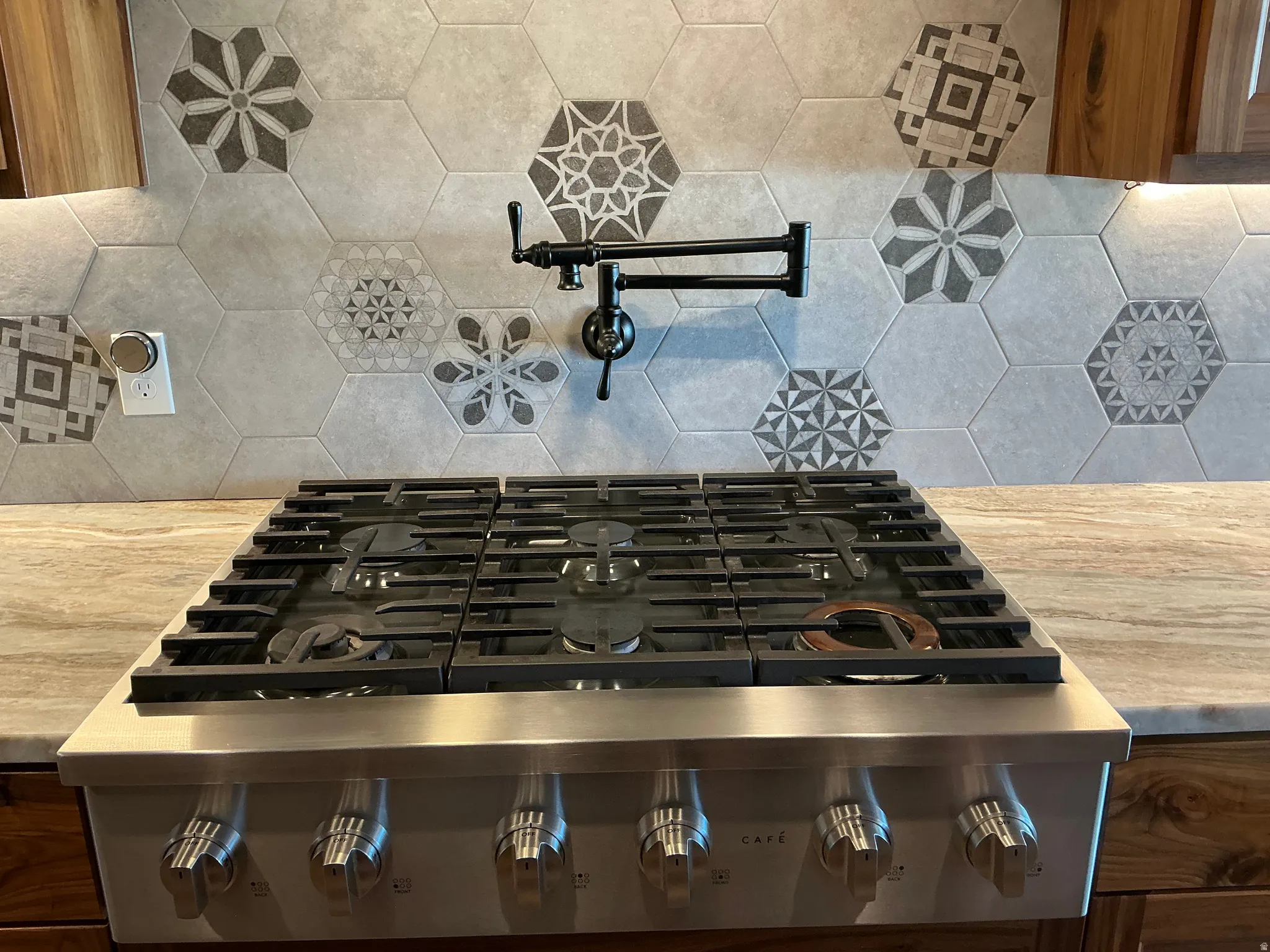 Kitchen view of pot filler, backsplash, and stainless steel gas stove