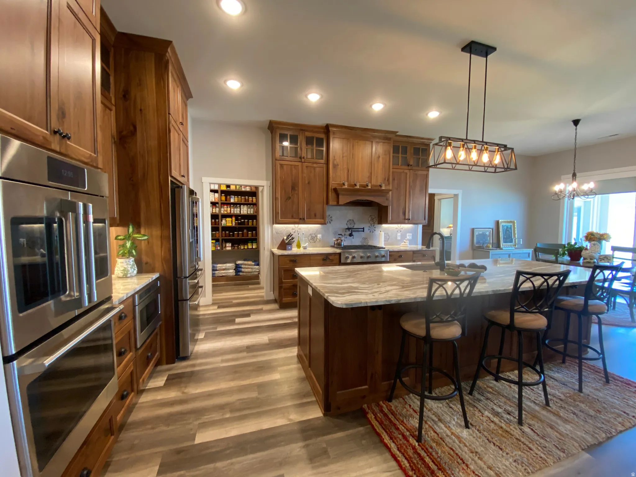 Kitchen with wood finish cabinets, stainless steel appliances, light stone counters, and a breakfast bar