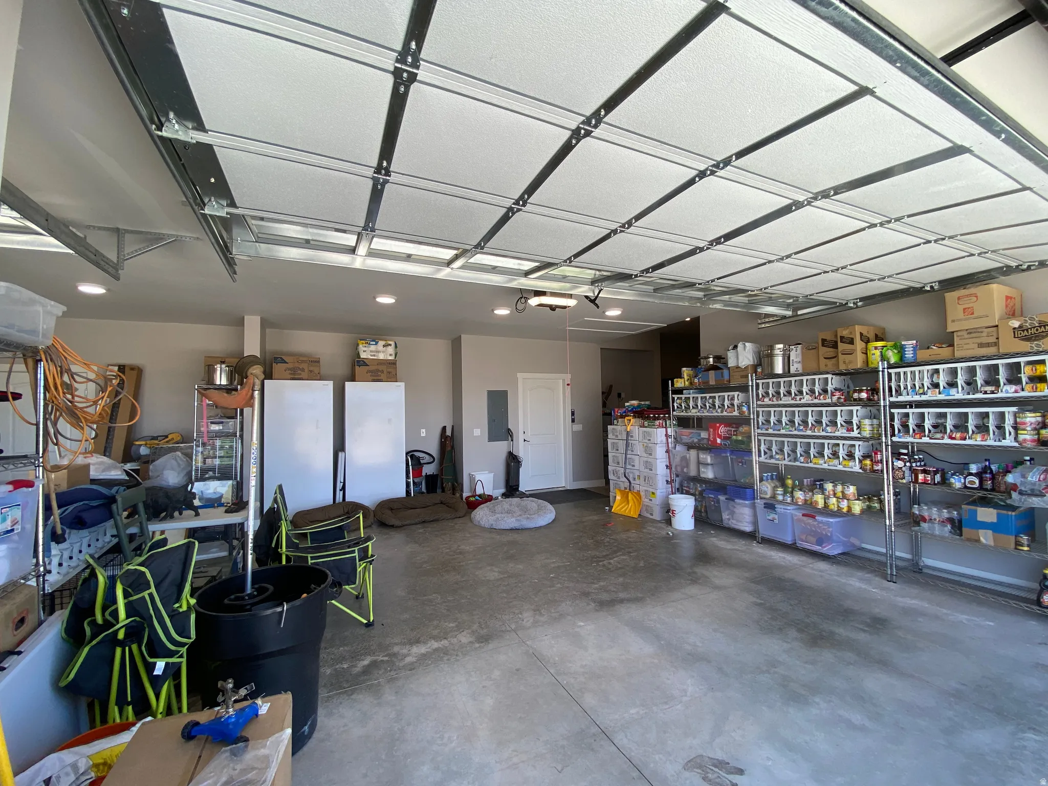 Garage with electric panel and freestanding refrigerator