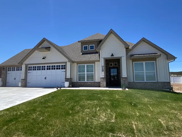 Craftsman house featuring roof with shingles, a front yard, stone siding, and an attached garage