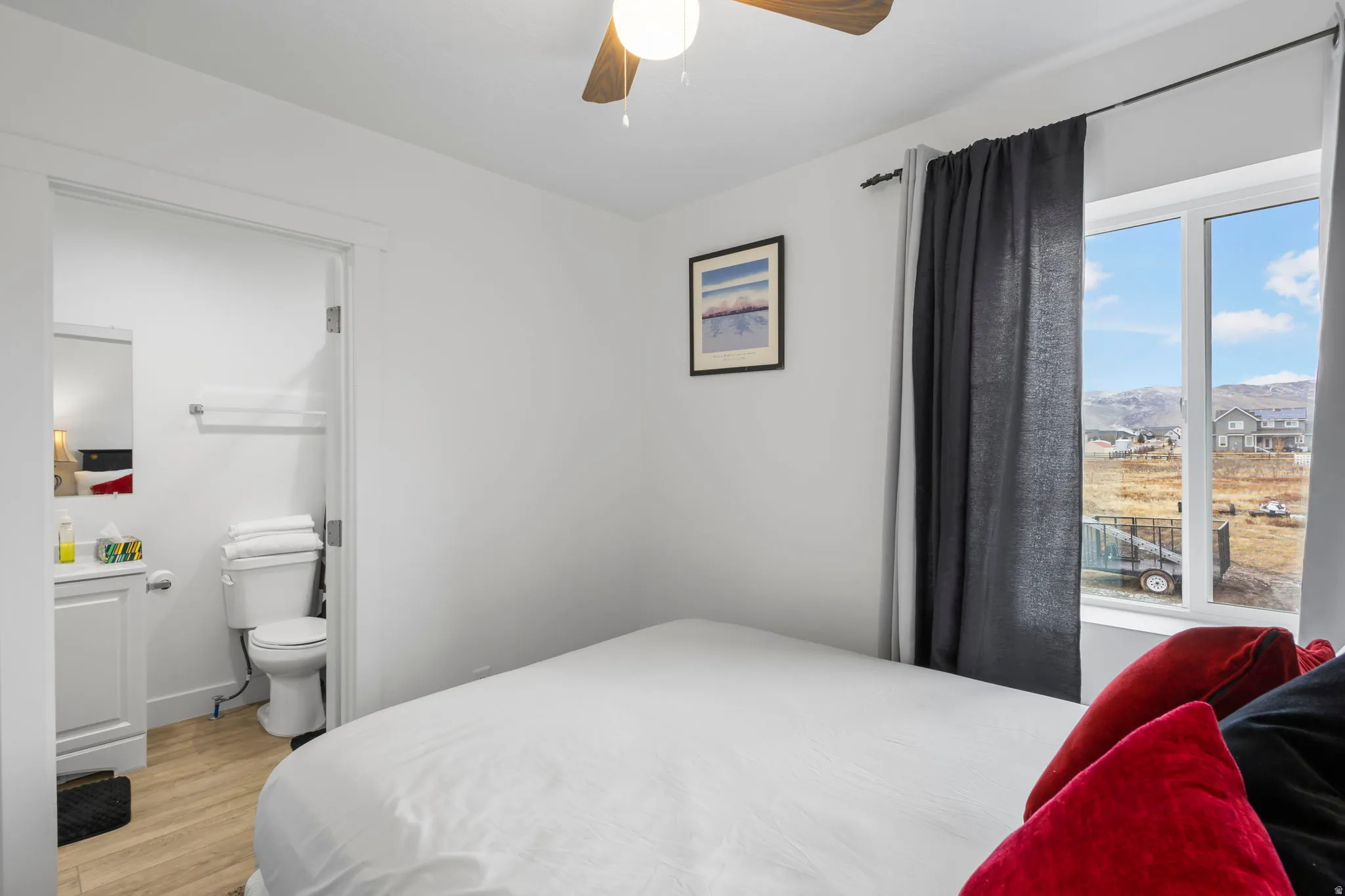 Bedroom with light wood finished floors, ceiling fan, and ensuite bath