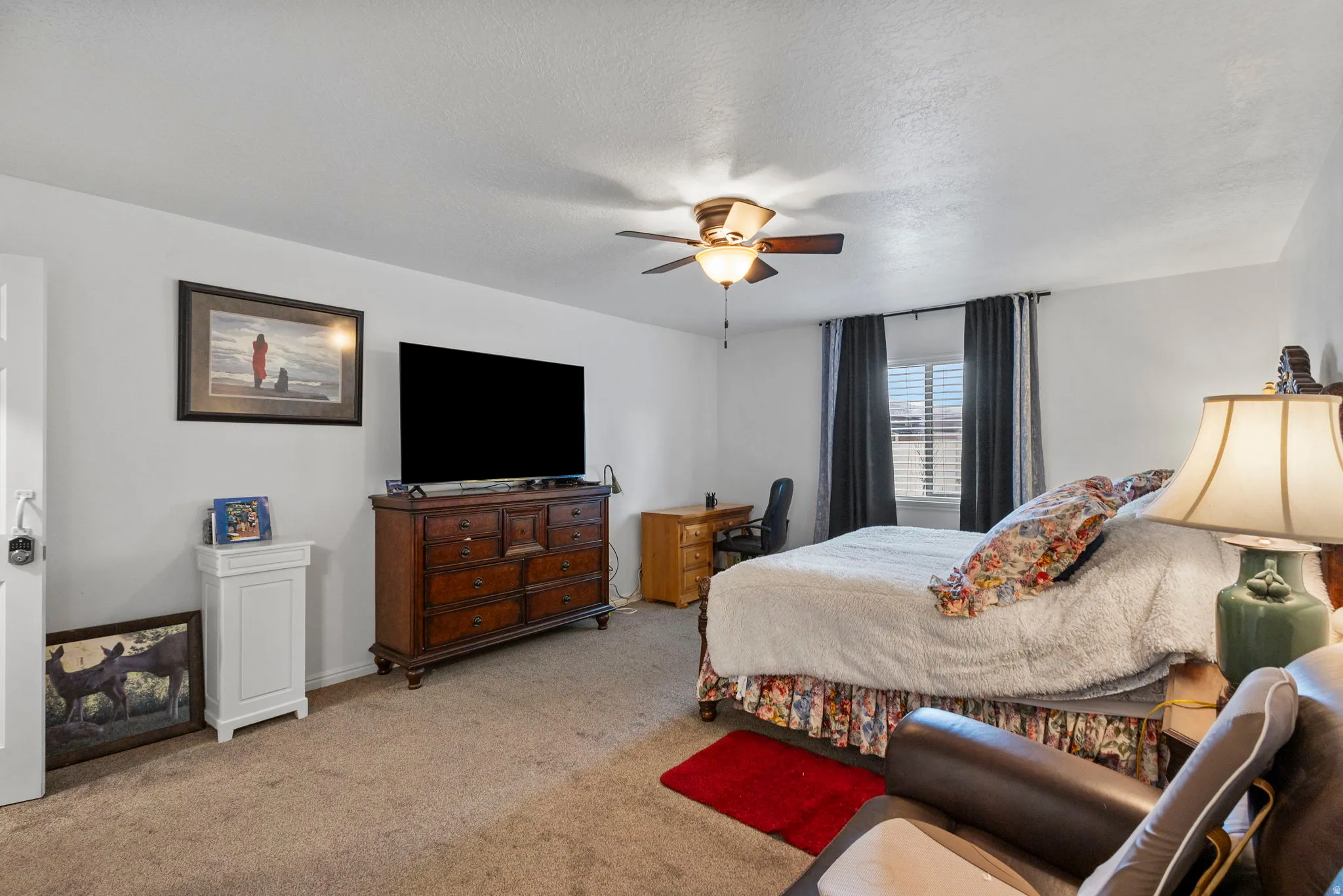 Carpeted bedroom with a ceiling fan and a textured ceiling