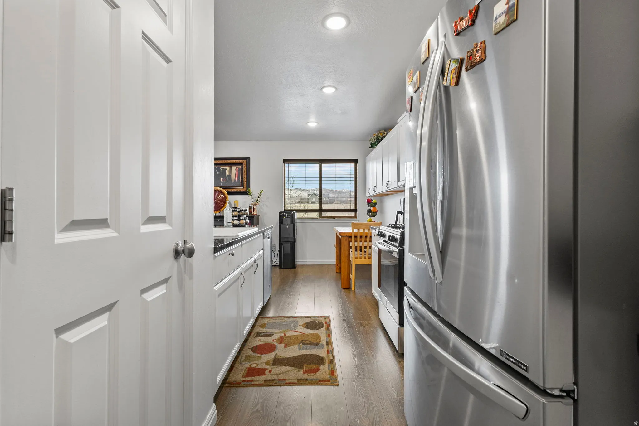 Kitchen with white cabinetry, stainless steel appliances, dark wood-style floors, light countertops, and recessed lighting