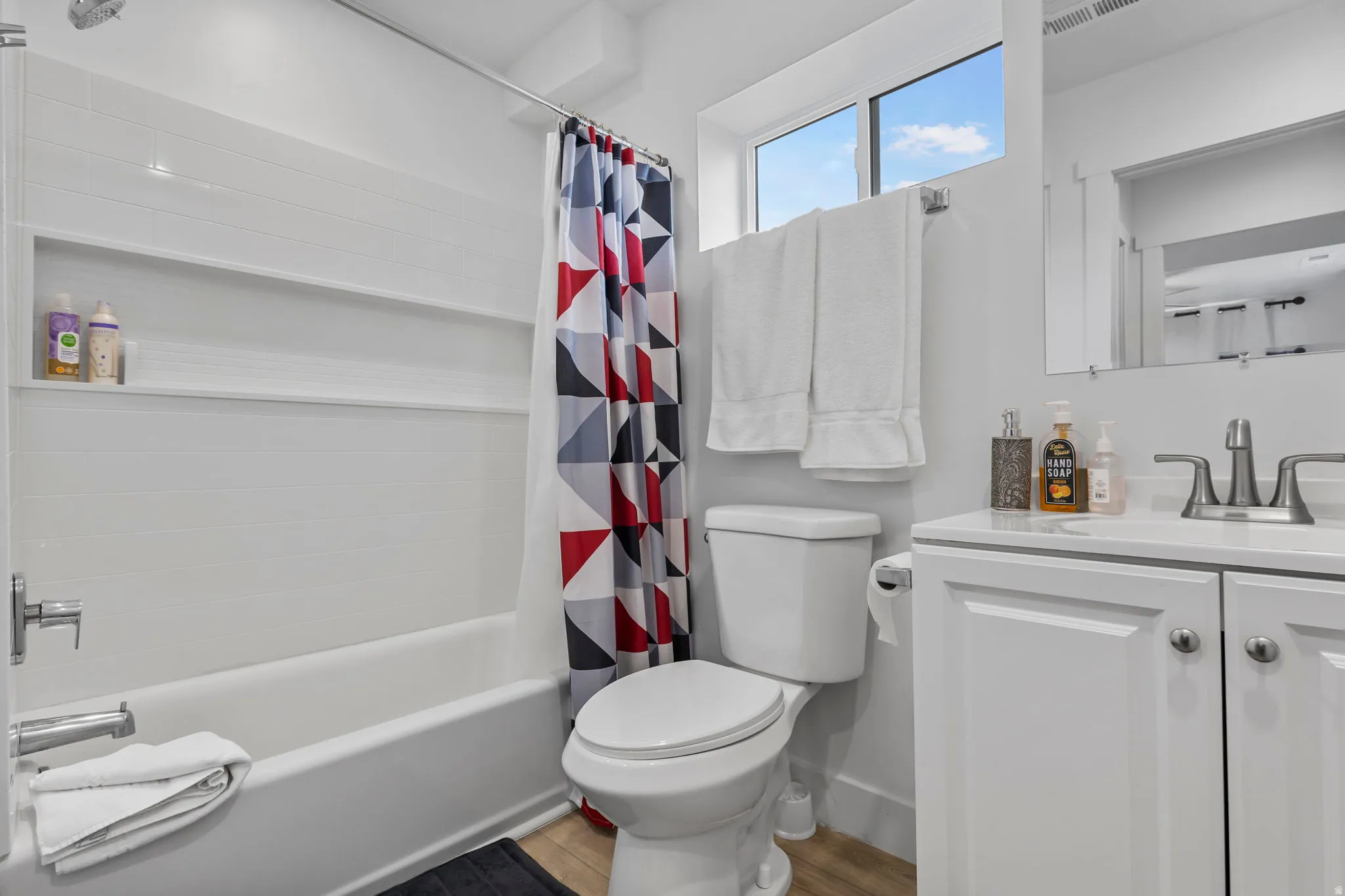Bathroom with vanity, shower / bath combination with curtain, and light wood-type flooring