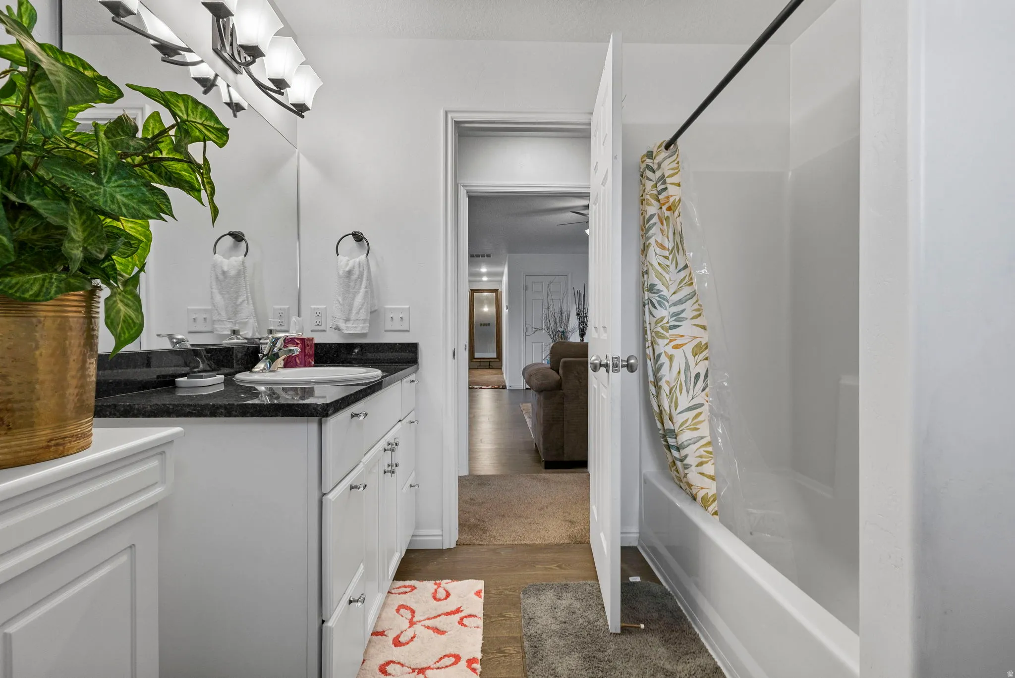 Bathroom with vanity, shower / tub combo with curtain, and dark wood-style flooring