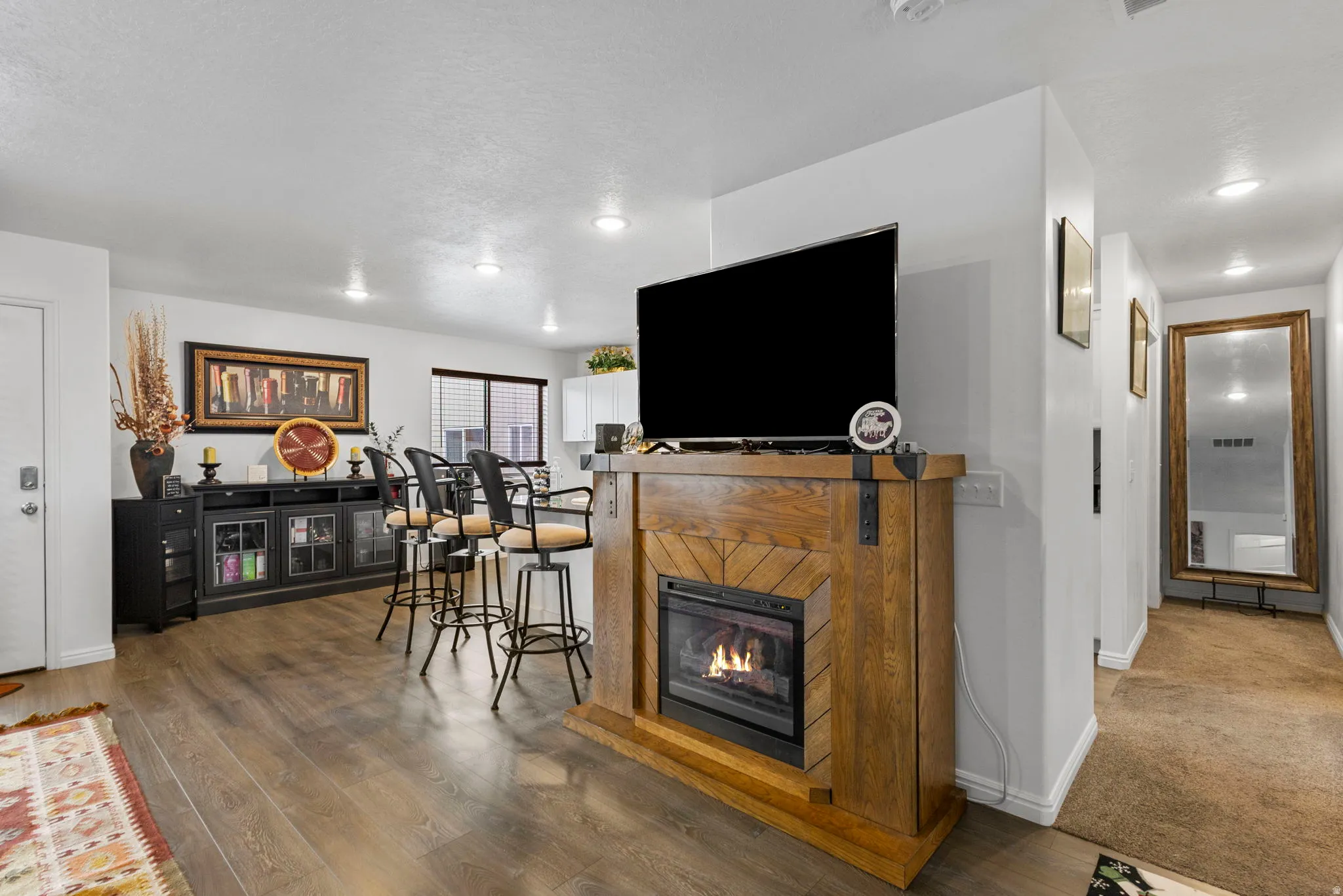 Living area with a glass covered fireplace, wood finished floors, and recessed lighting