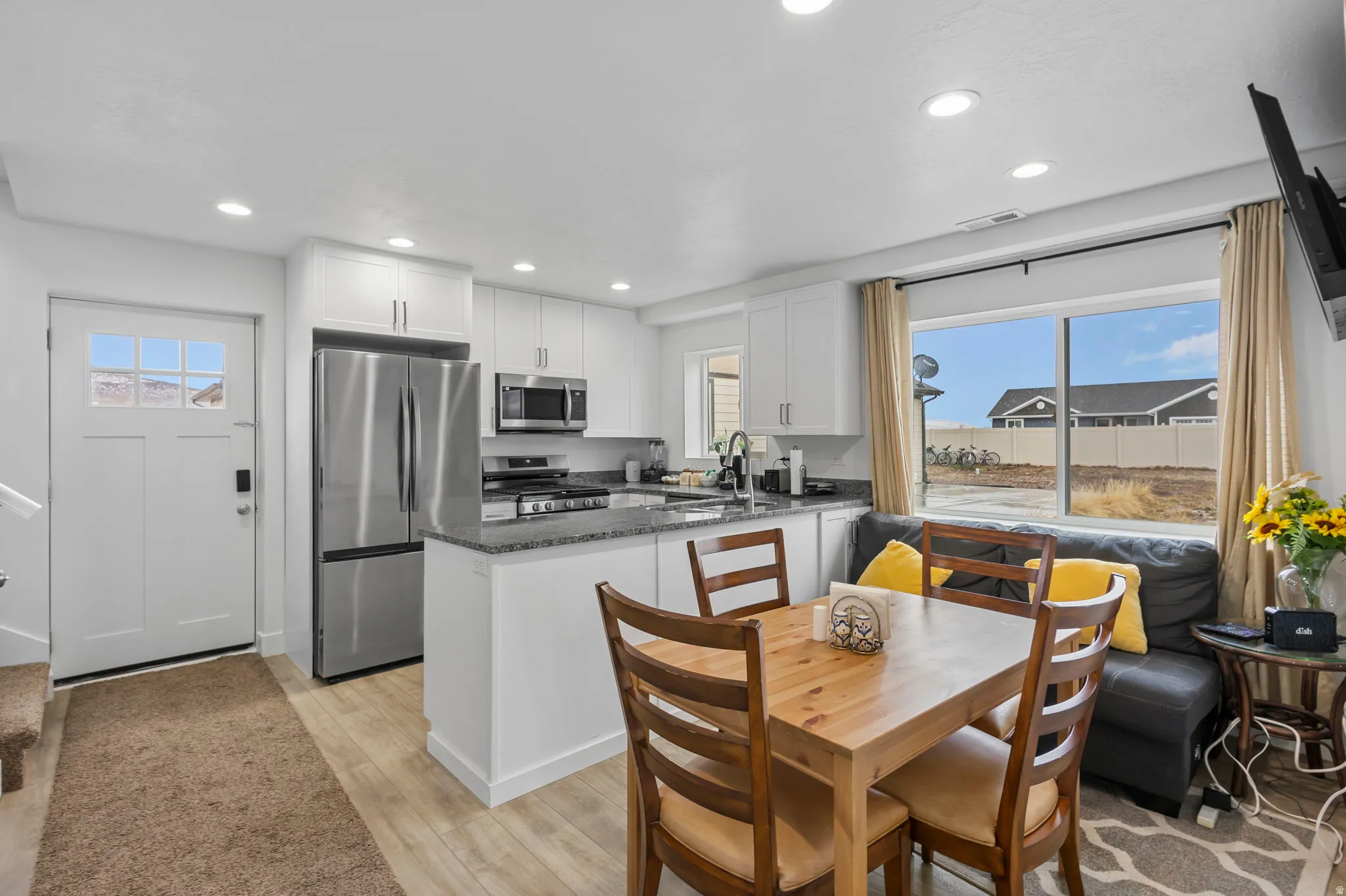 Kitchen with dark stone countertops, stainless steel appliances, white cabinets, a peninsula, and recessed lighting