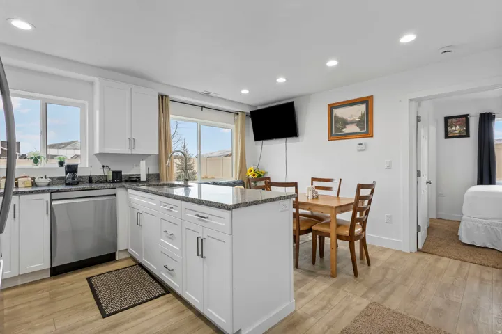 Kitchen featuring dark stone countertops, white cabinets, recessed lighting, stainless steel appliances, and light wood-style flooring