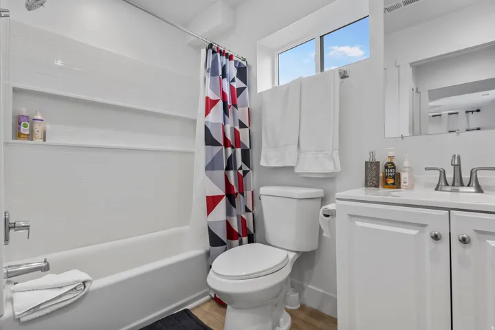 Bathroom with vanity, shower / bath combination with curtain, and light wood-type flooring