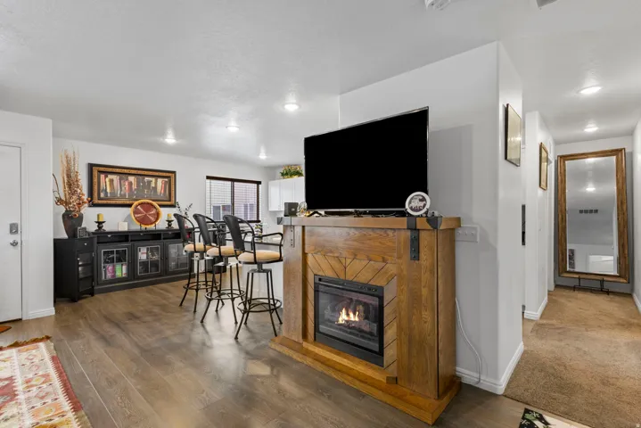 Living area with a glass covered fireplace, wood finished floors, and recessed lighting