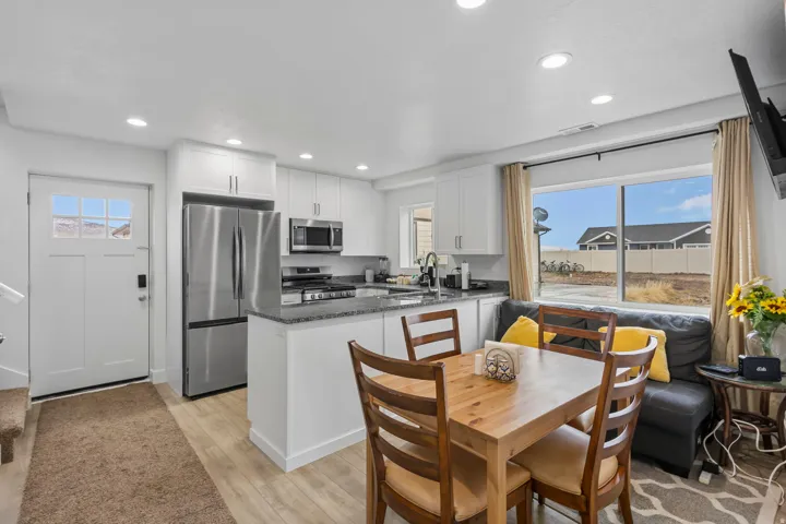 Kitchen with dark stone countertops, stainless steel appliances, white cabinets, a peninsula, and recessed lighting
