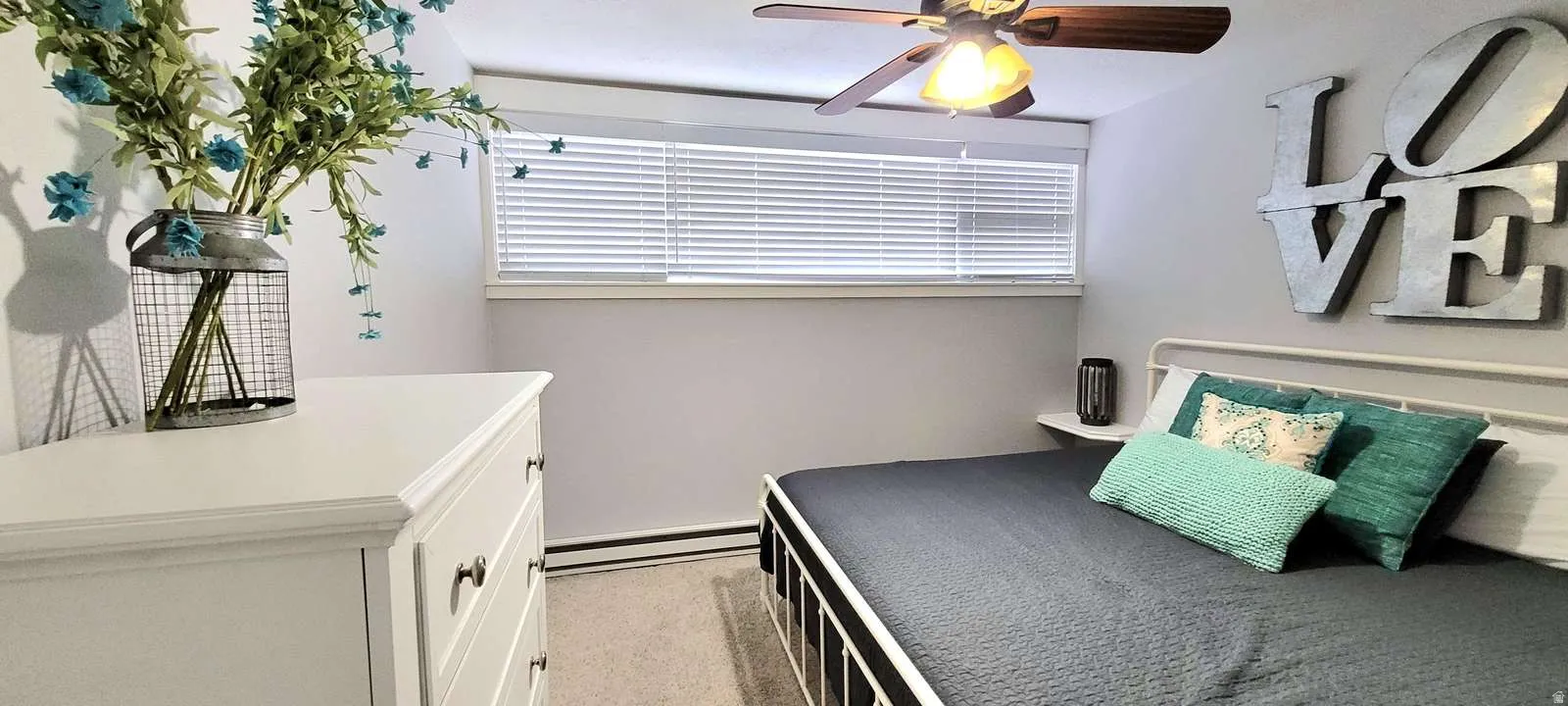 Bedroom with baseboard heating, light carpet, and a ceiling fan