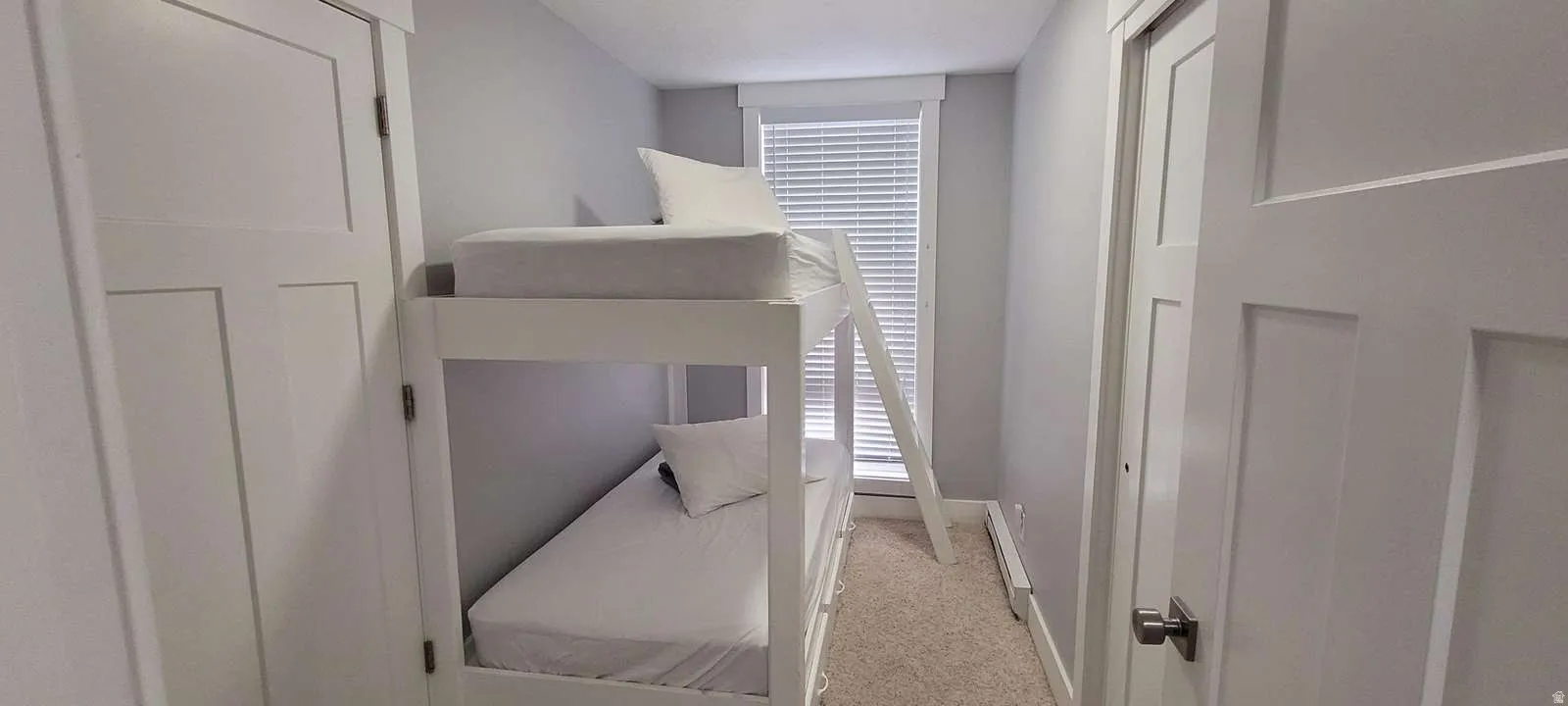 Bedroom with light colored carpet and a baseboard radiator