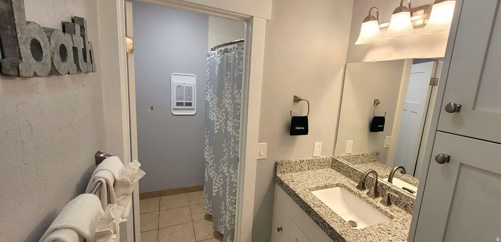 Full bathroom featuring a shower with curtain, vanity, and light tile patterned floors