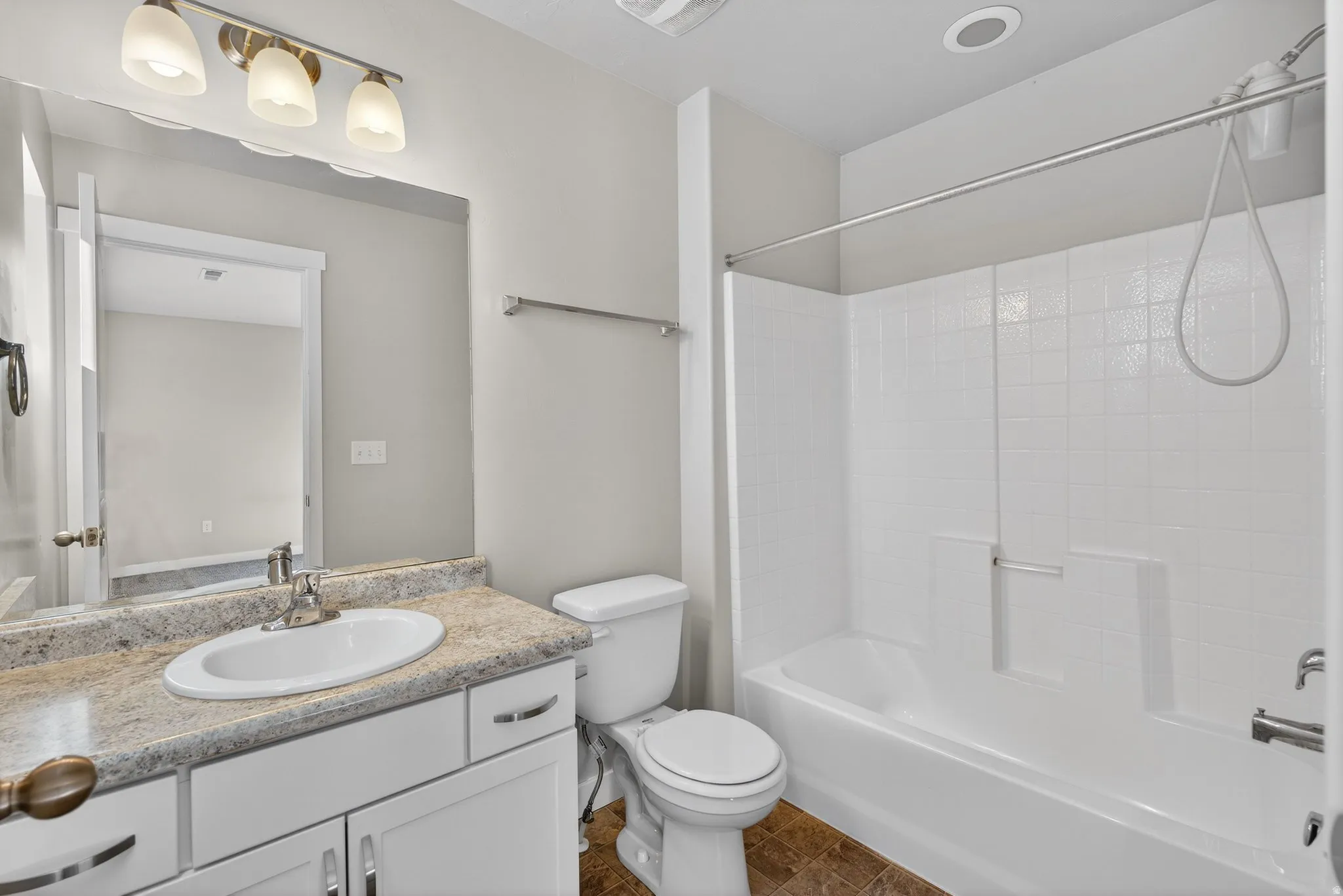 Bathroom featuring  shower combination, vanity, and dark tile patterned floors