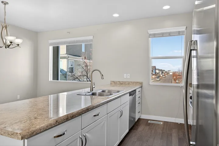 Kitchen featuring stainless steel appliances, a peninsula, light countertops, white cabinetry, and dark wood-type flooring
