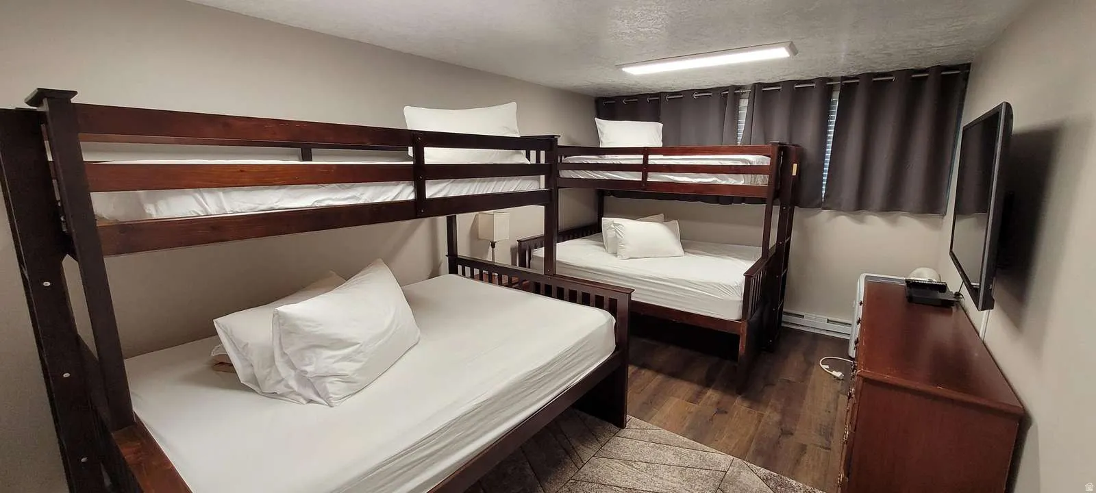Bedroom with dark wood finished floors, a textured ceiling, and baseboard heating