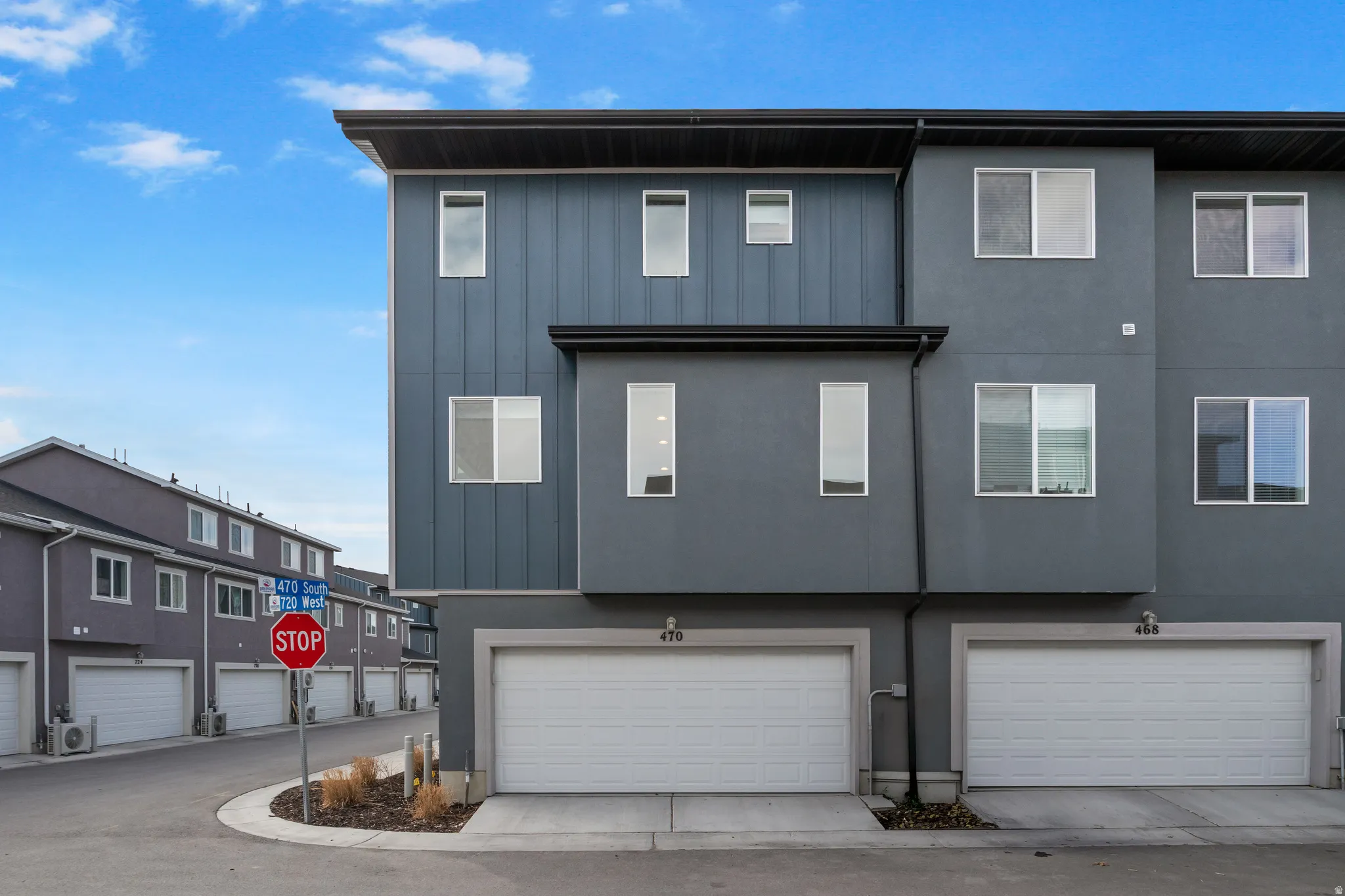 Back of property with a garage, board and batten siding, stucco siding, and concrete driveway