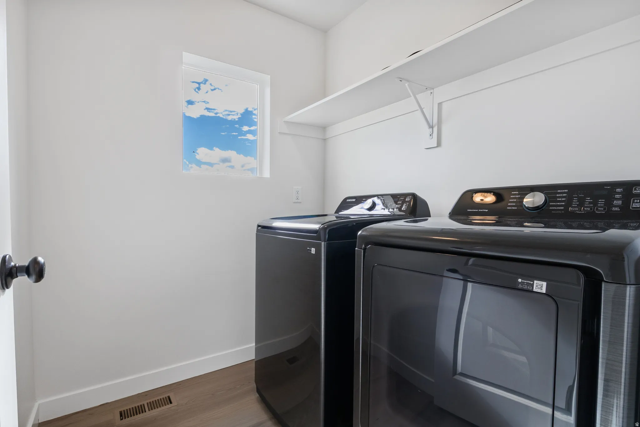 Laundry area with wood finished floors and washer and clothes dryer