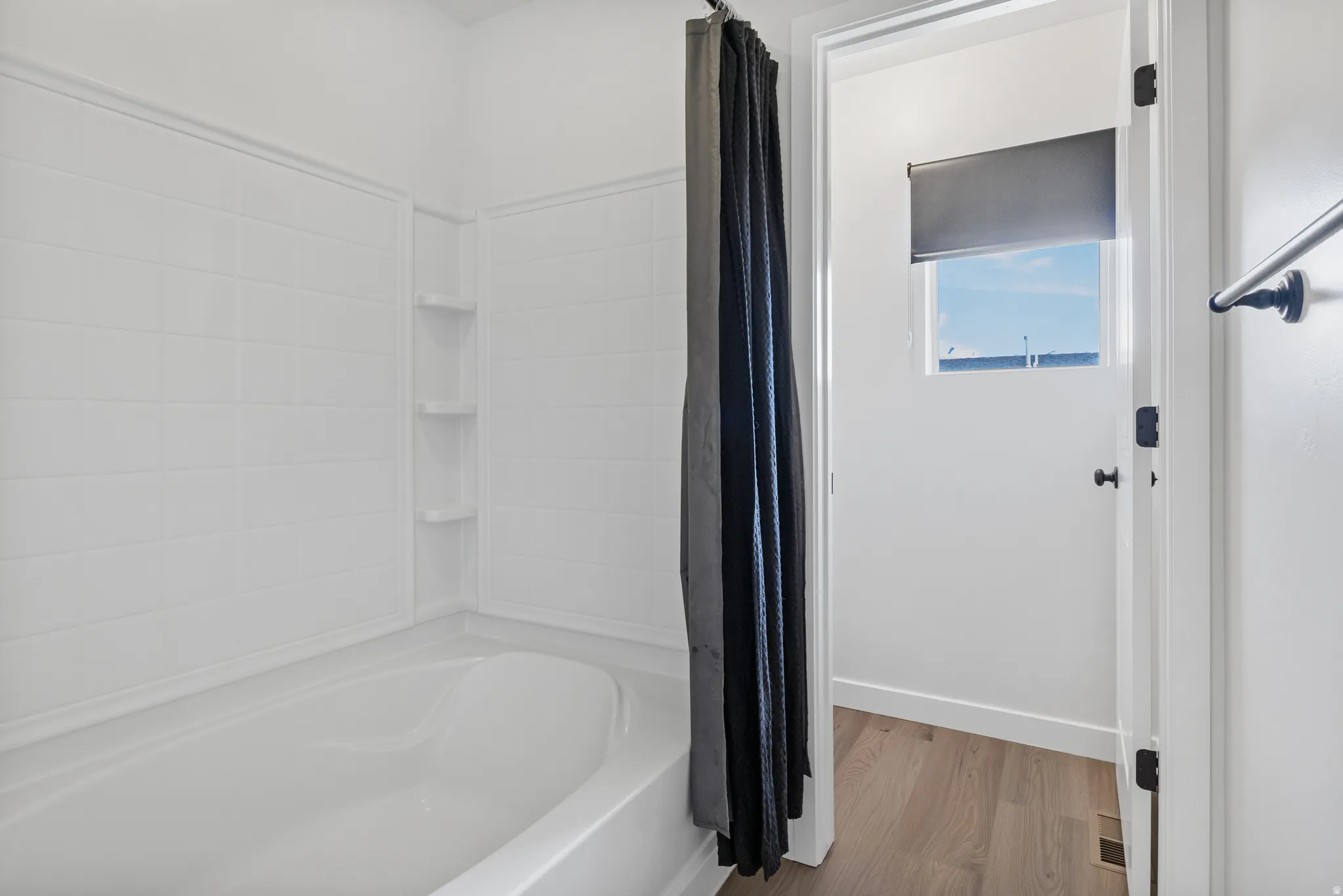 Full bath with shower / tub combo and light wood-style flooring