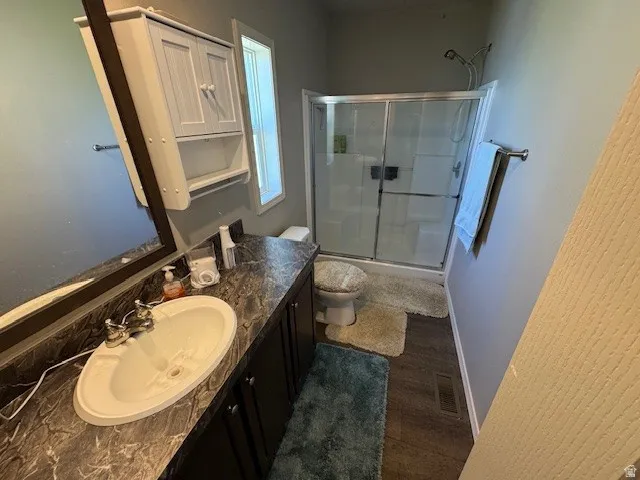 Bathroom with vanity, dark wood-style floors, and bath / shower combo with glass door
