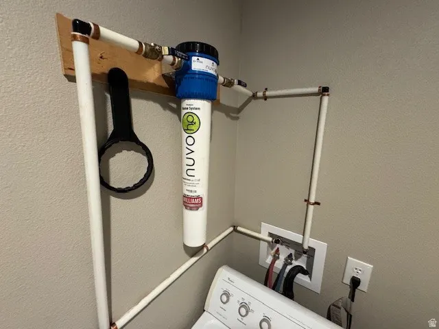 Laundry room featuring a textured wall and washer / clothes dryer