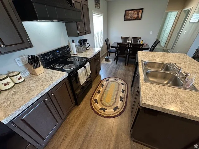 Kitchen with dark wood finished floors, black / electric stove, light countertops, and a kitchen island