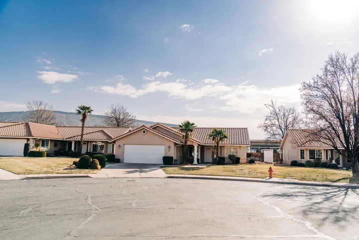 View of front facade with a tile roof, concrete driveway, a residential view, and stucco siding