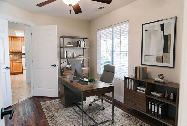 Home office with a ceiling fan and dark wood-type flooring