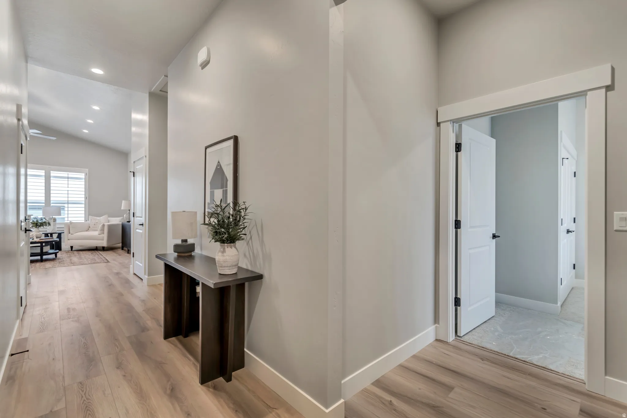 Hallway with light wood-style flooring, lofted ceiling, and recessed lighting