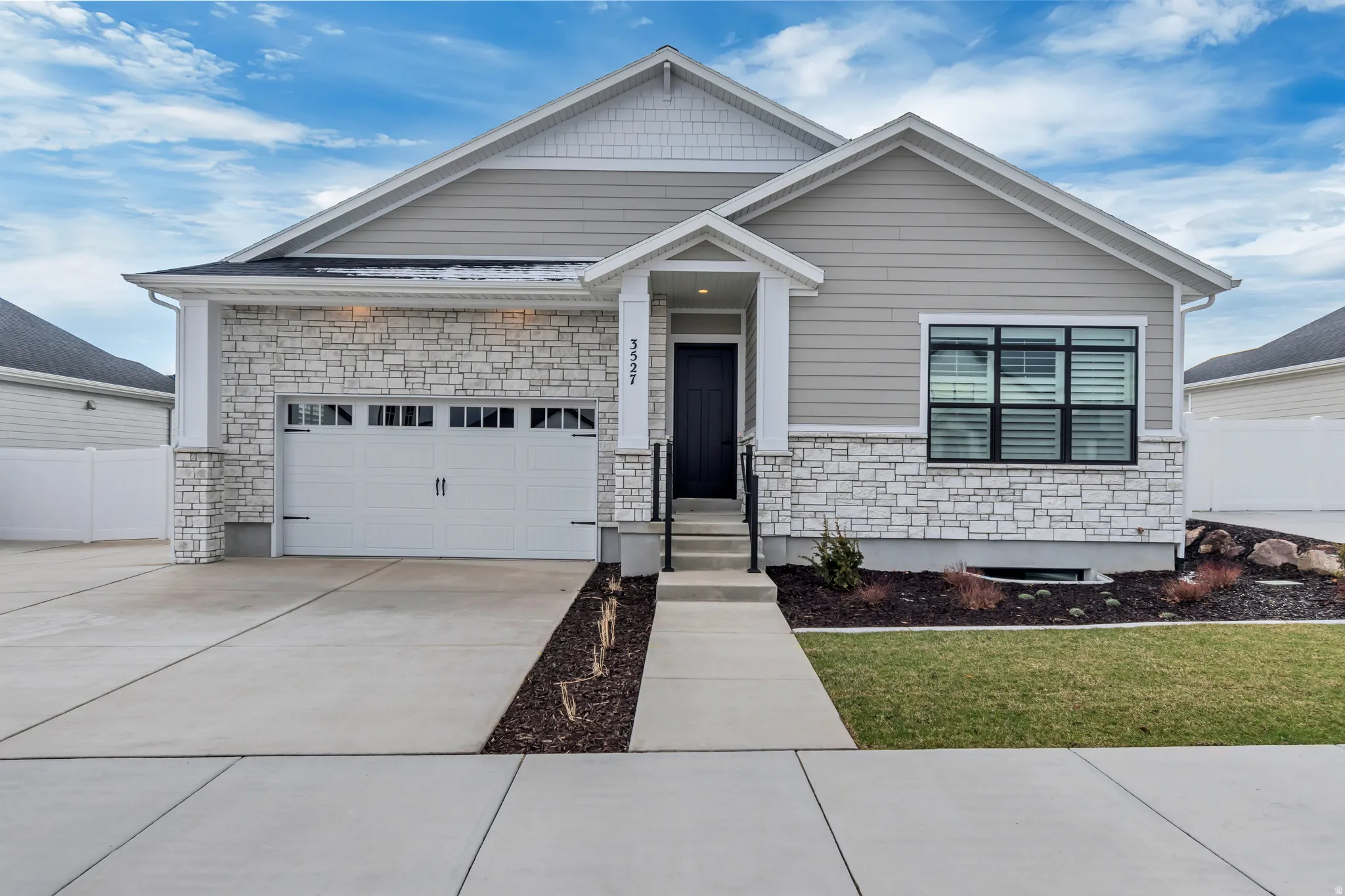 View of front of home with stone siding, driveway, and an attached garage