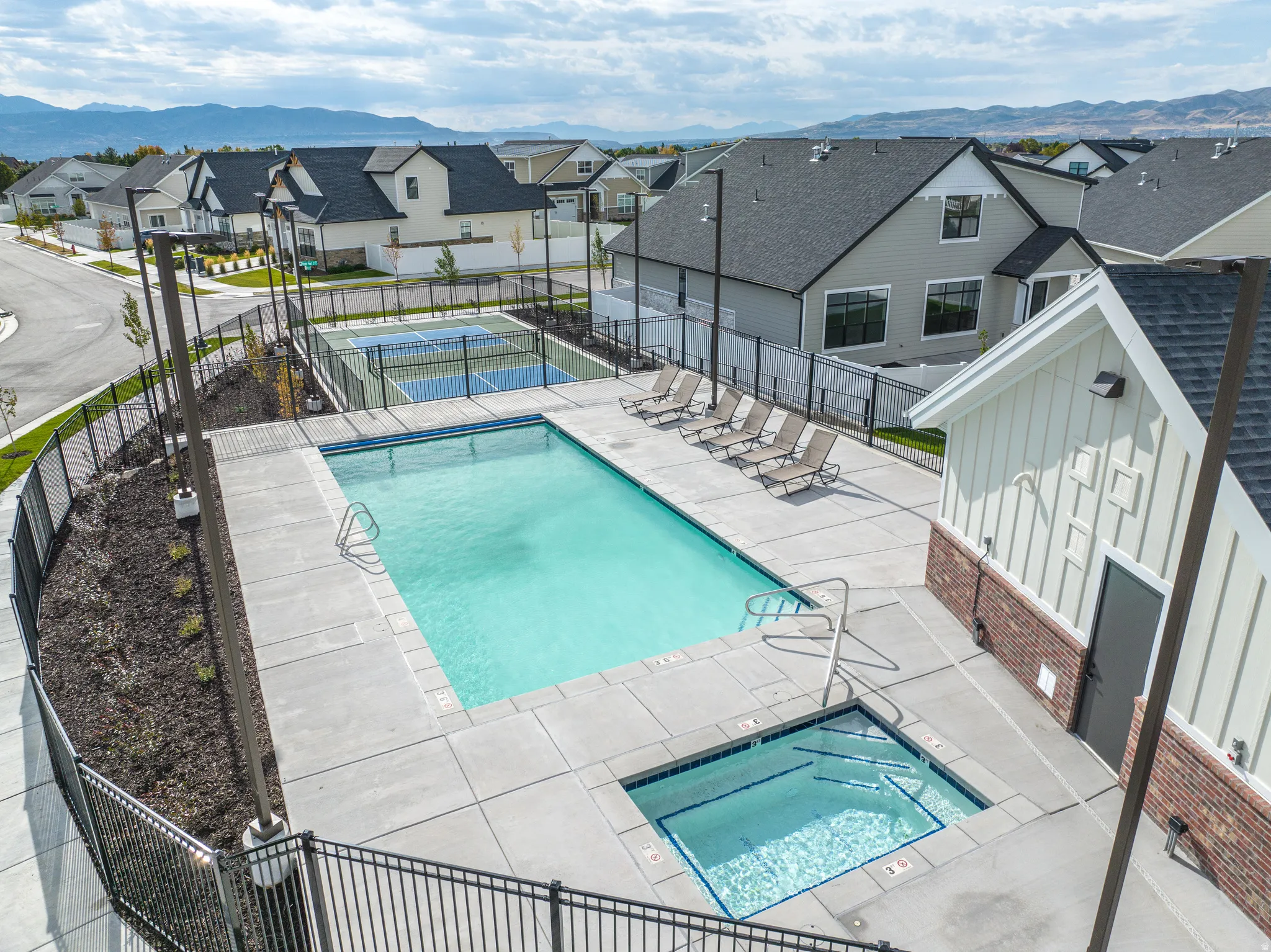 Community pool featuring a patio, a residential view, a mountain view, and a hot tub