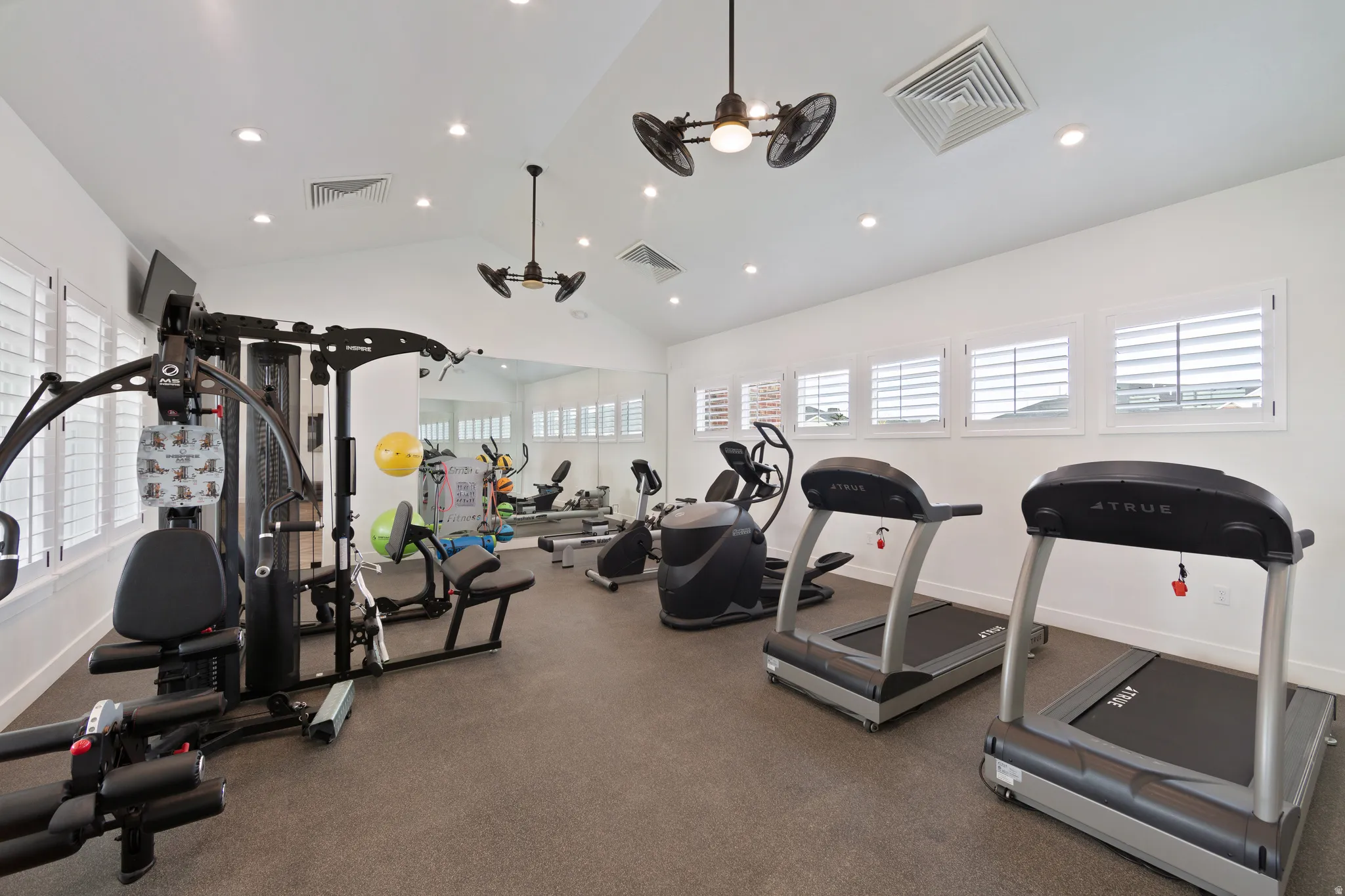 Workout area featuring recessed lighting, ceiling fan, and a high ceiling