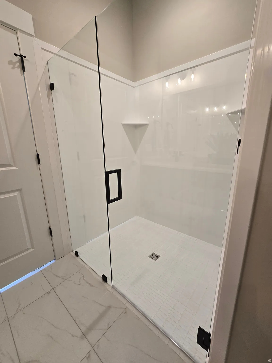 Bathroom with a shower stall and marble finish floors