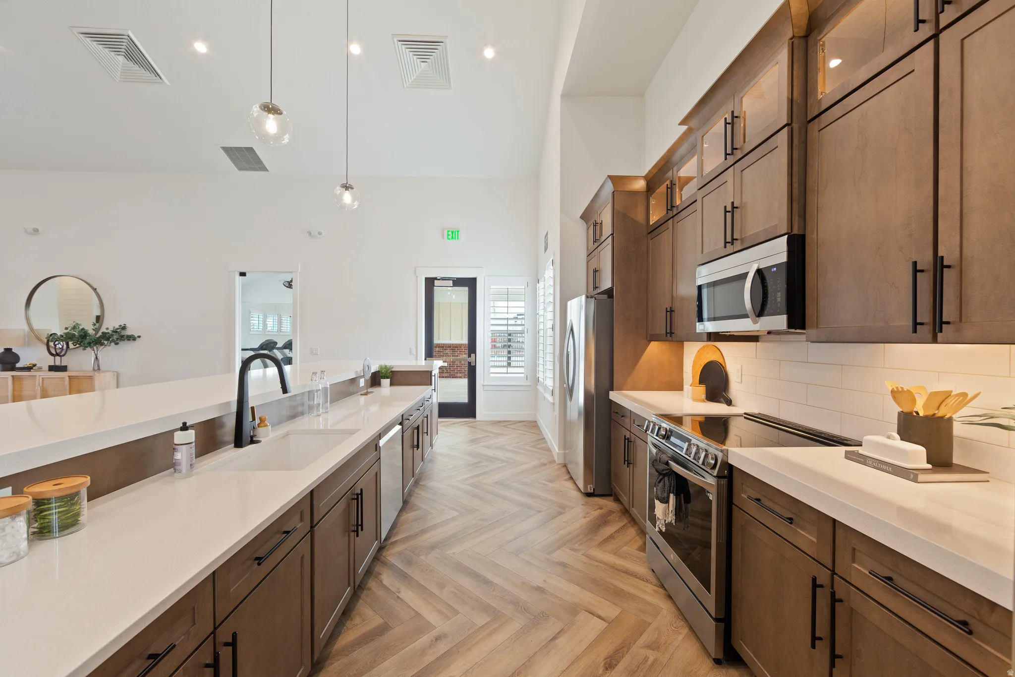 Kitchen with stainless steel appliances, pendant lighting, parquet flooring, glass insert cabinets, and tasteful backsplash