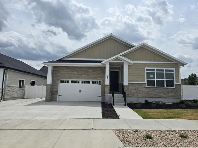 Craftsman inspired home featuring stone siding, driveway, board and batten siding, and an attached garage