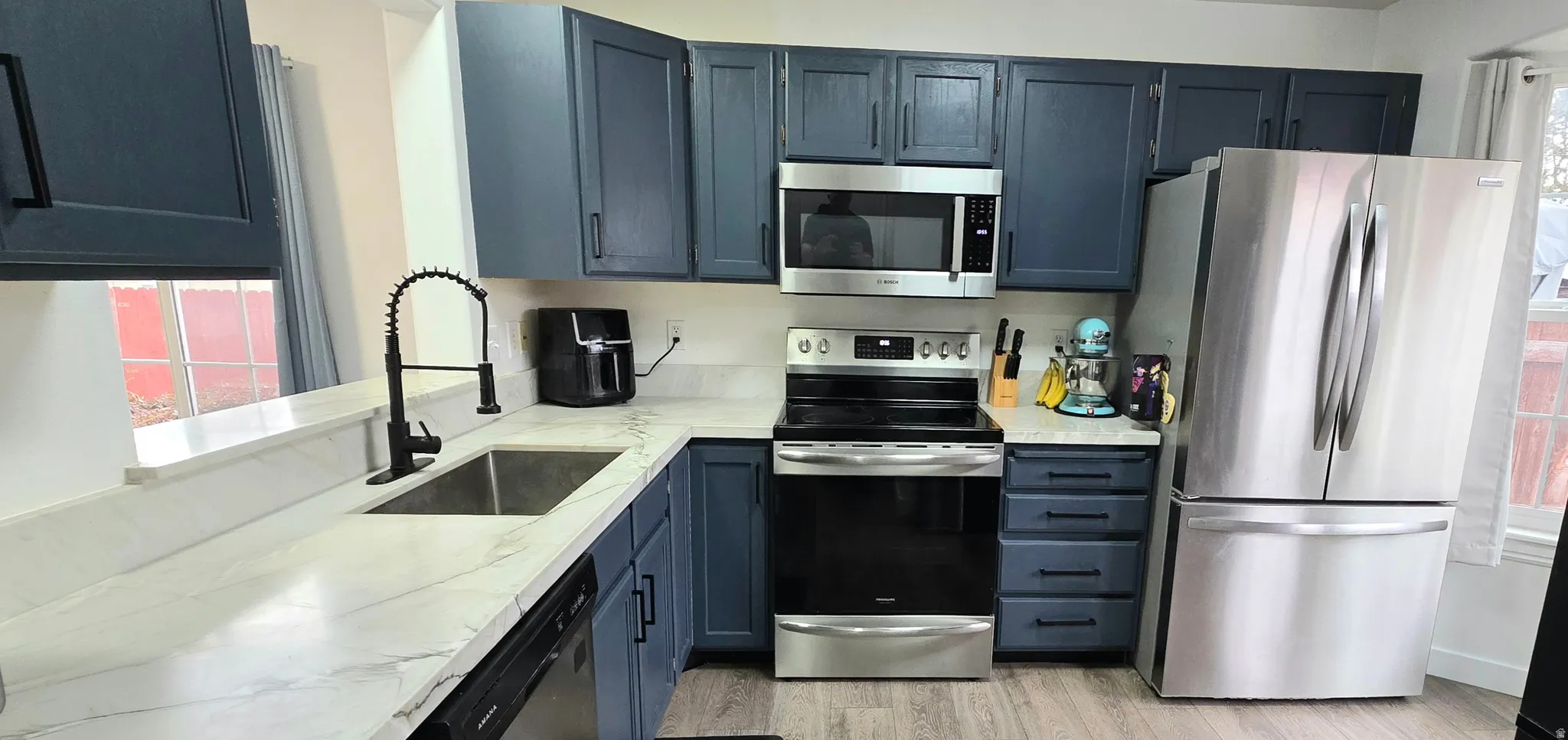 Kitchen featuring new stainless steel appliances, wood-style floors, and Quartzite stone countertops
