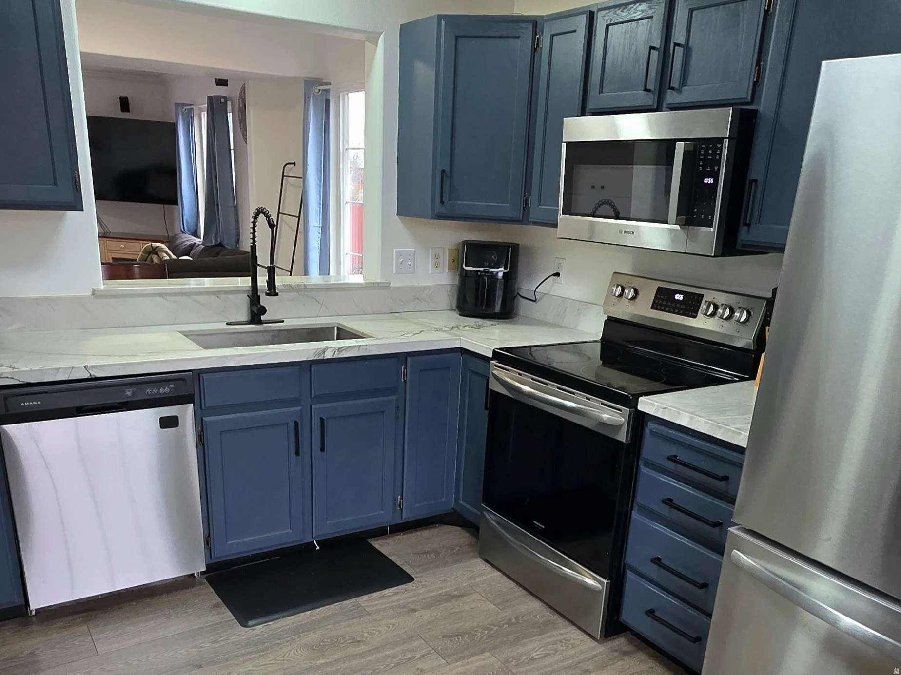 Kitchen featuring new stainless steel appliances, wood-style floors, and Quartzite stone countertops
