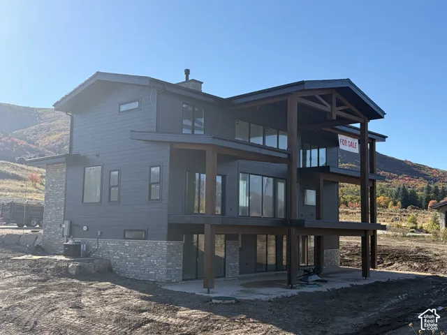 Contemporary architecture featuring a dark gray facade, expansive windows, stone veneer accents, and exposed wood beam structural elements
